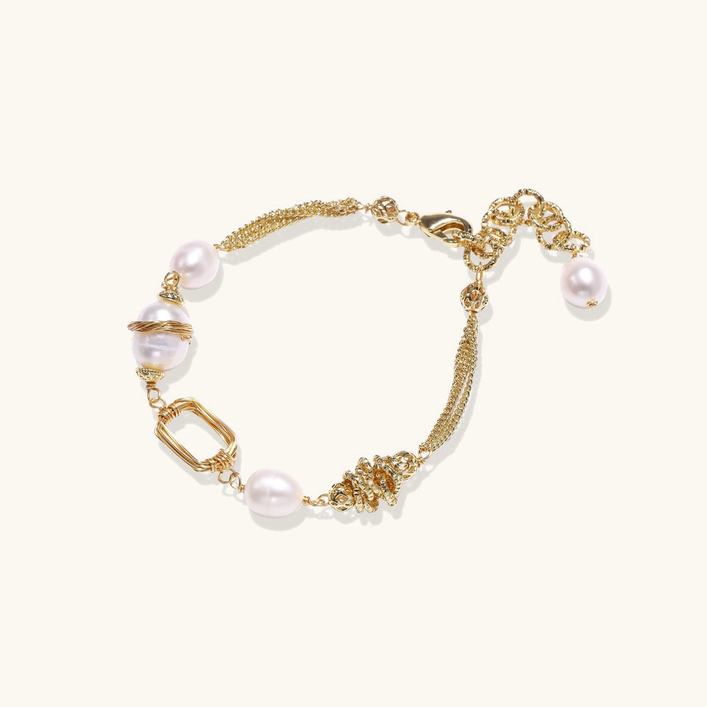 Gold-plated bracelet featuring cream freshwater pearls and decorative chain links on white background.