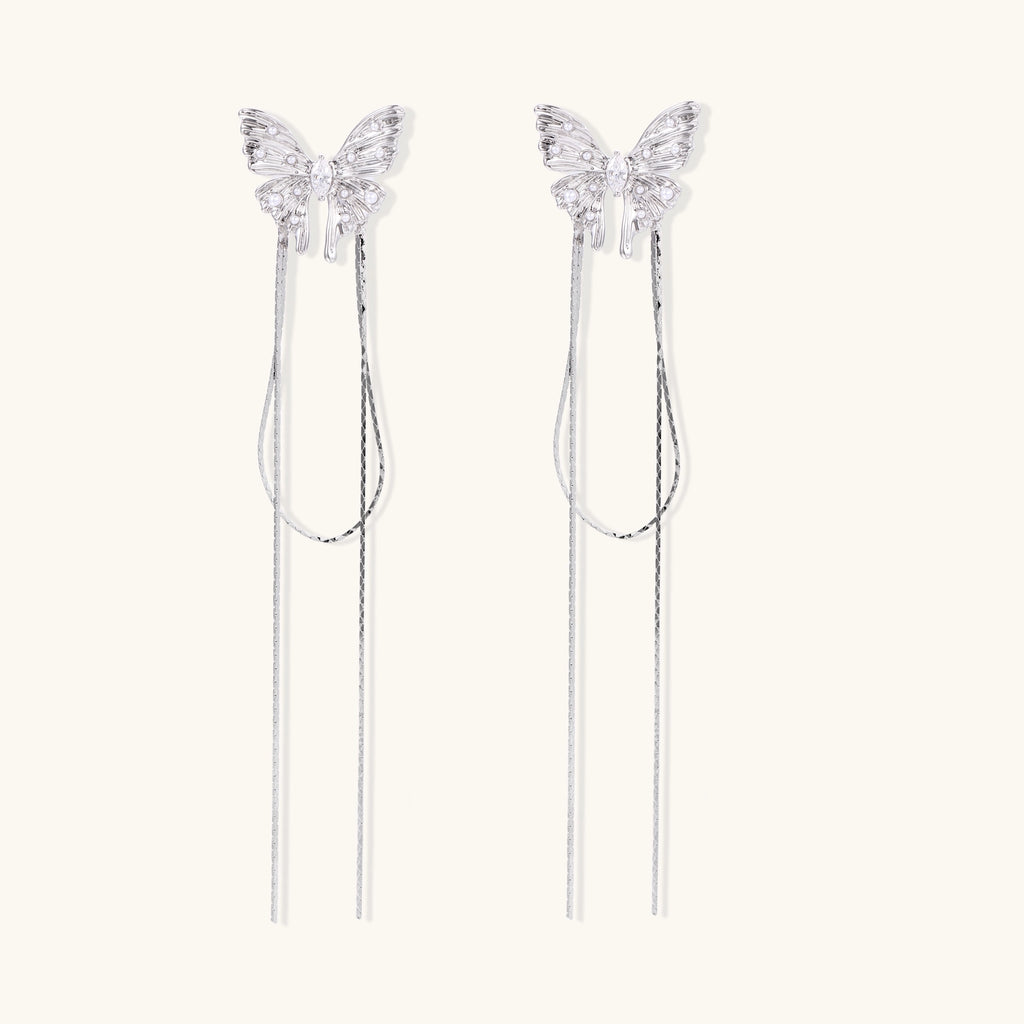 Delicate drop earrings with clear crystal butterfly tops and long metallic chain dangles on white background.