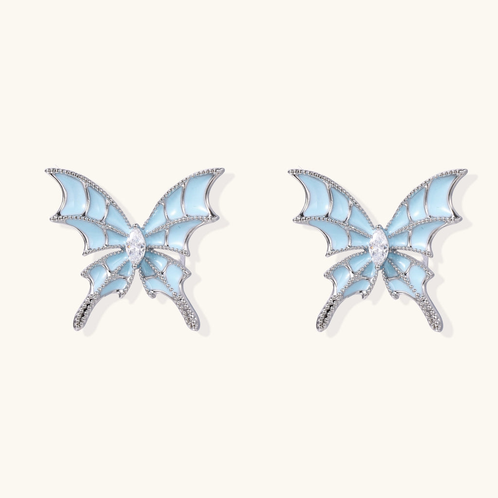Blue enamel butterfly earrings with cascading gold-plated chains and zirconia crystal accents on white background.