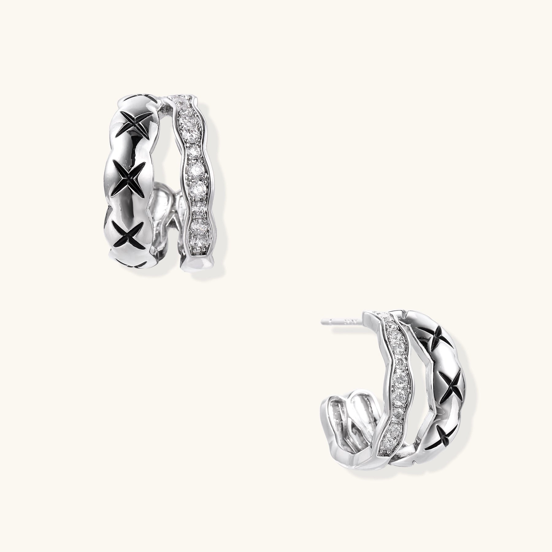 Close-up of gold-plated huggie earrings featuring X-pattern band and wavy zirconia-set band on white background.