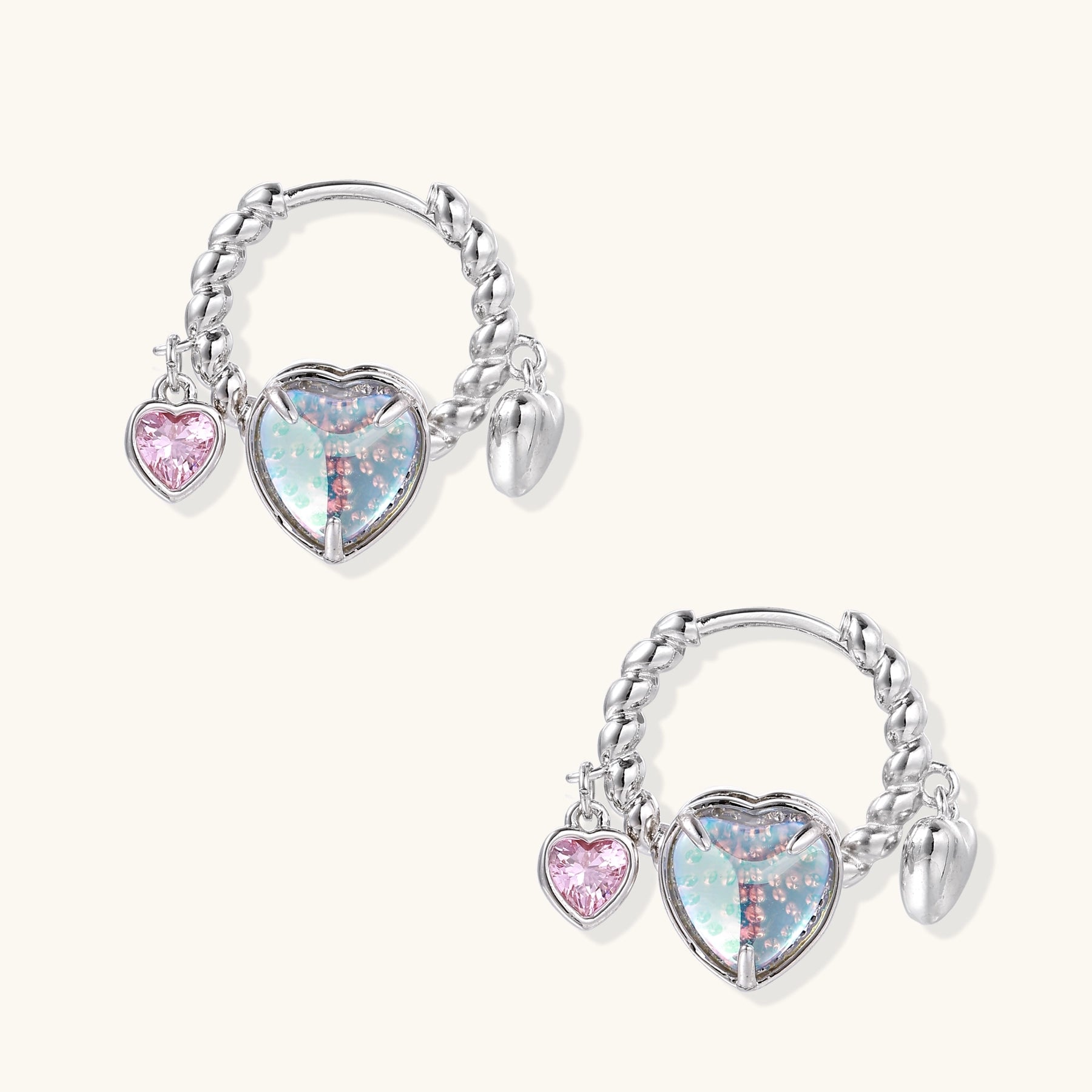 Gold-plated brass hoop earrings with three heart charms including iridescent turquoise and pink hearts on white background.