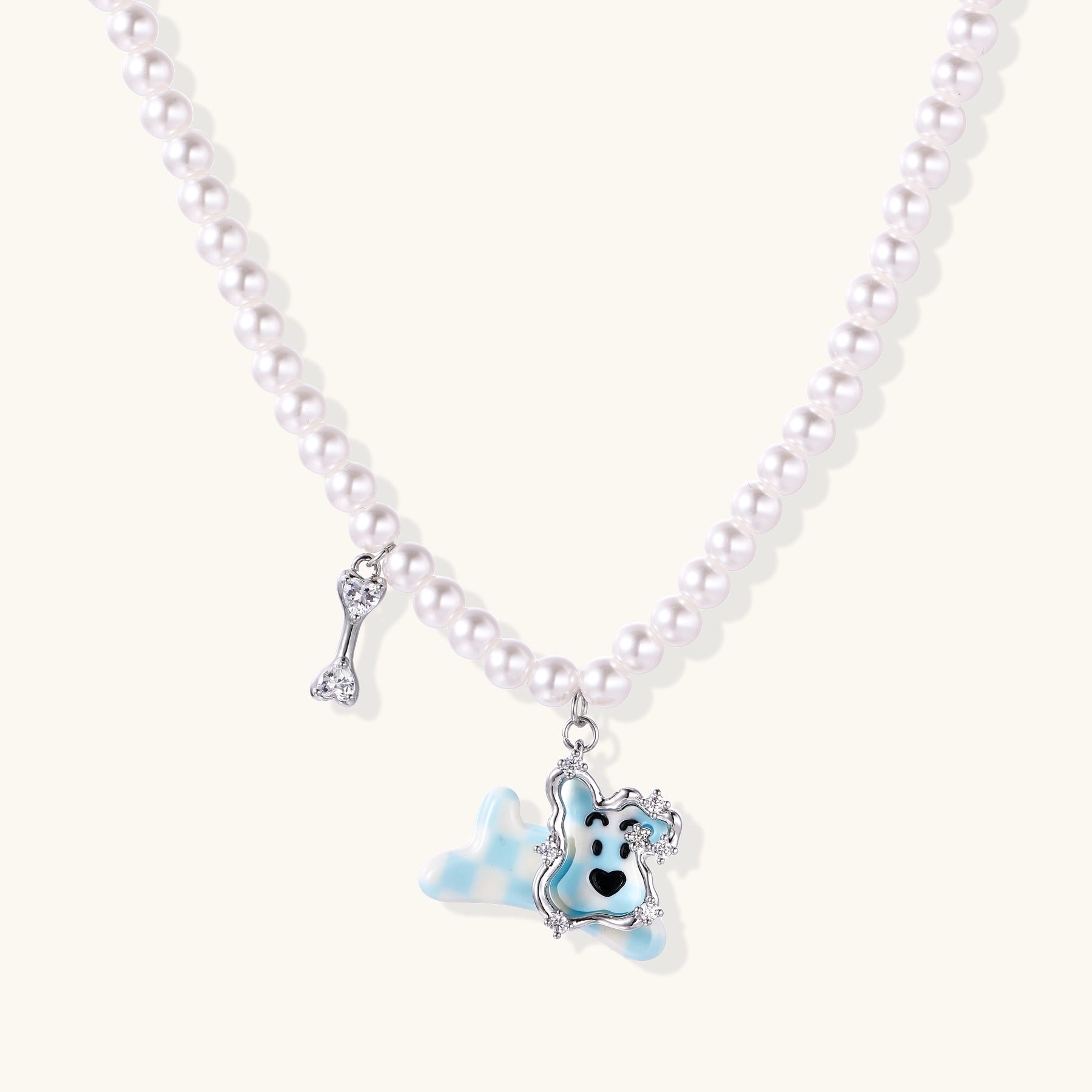 Pearl necklace with adorable blue dog pendant featuring crystal accents and bone charm on neutral background