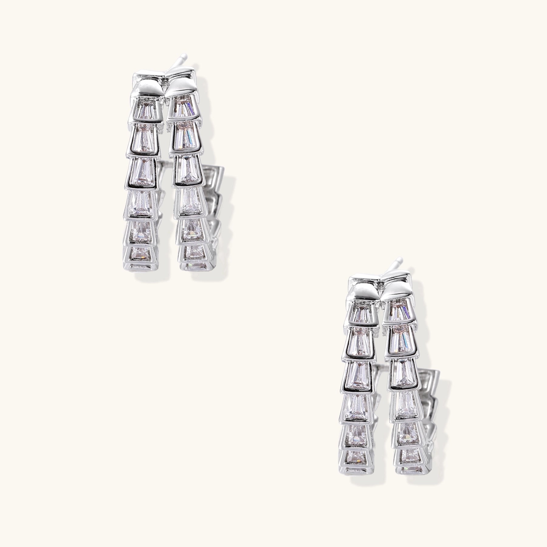 Gold-plated huggie hoops featuring vertical rows of clear baguette zirconia stones in geometric linear design