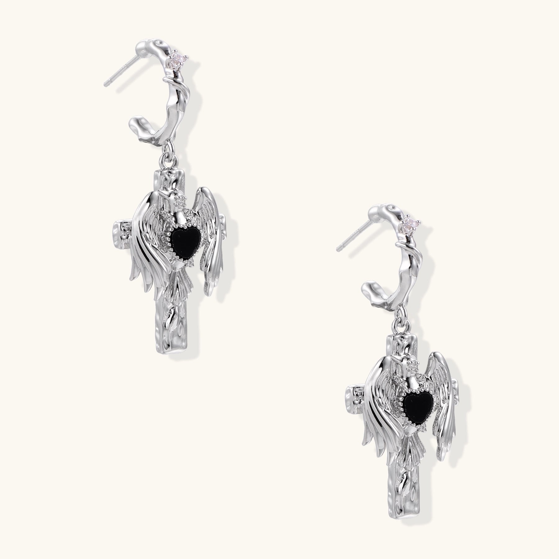 Gold-plated brass earrings with winged design, black heart-shaped zirconia center, and crystal accents on white background.