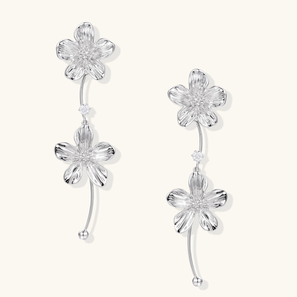 Gold-plated floral dangle earrings with zirconia crystal centers and curved stems on white background.