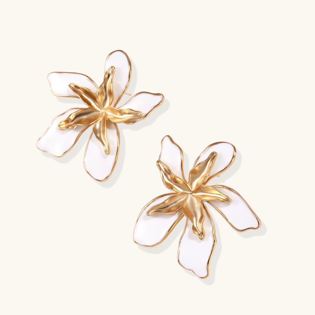 Large floral stud earrings with gold-plated brass petals and white enamel centers on neutral background