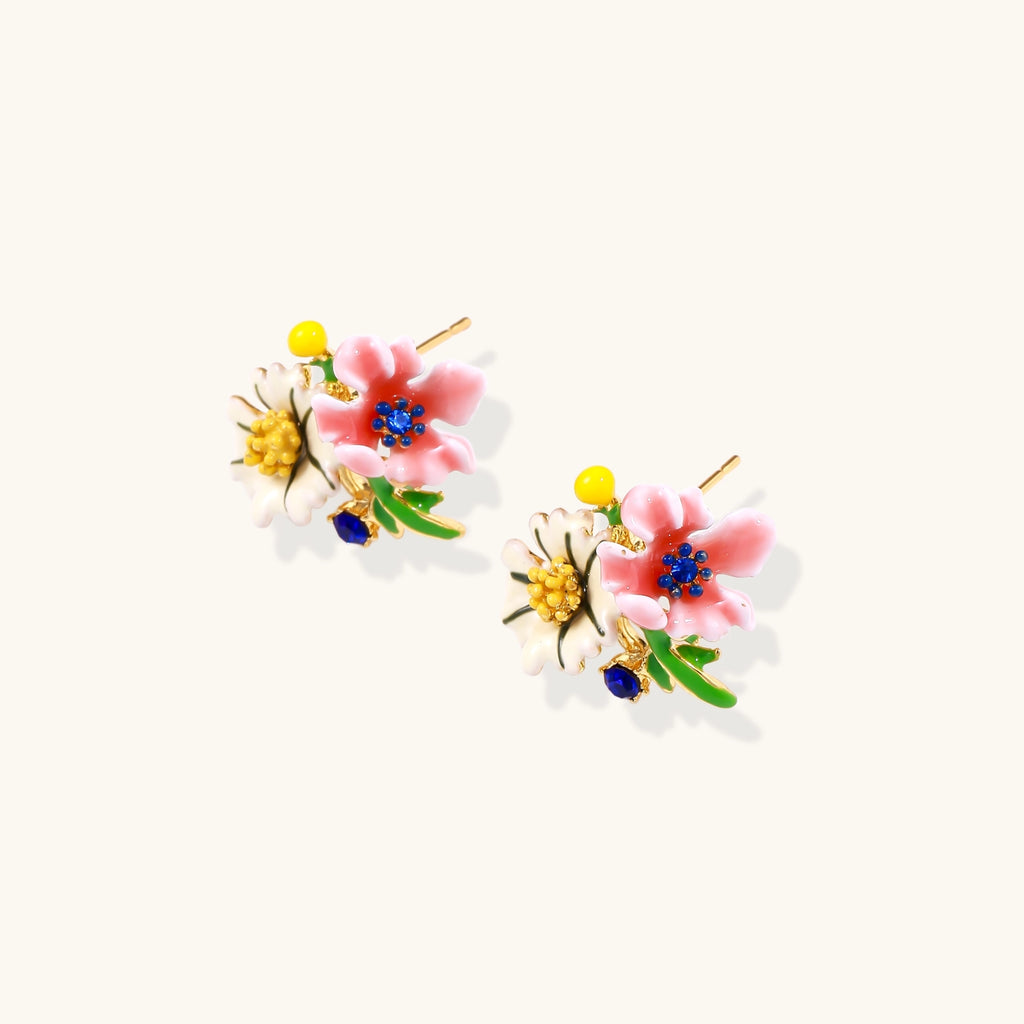 Detailed view of gold-plated brass stud earrings featuring multicolor enamel flowers with white, pink, and blue petals