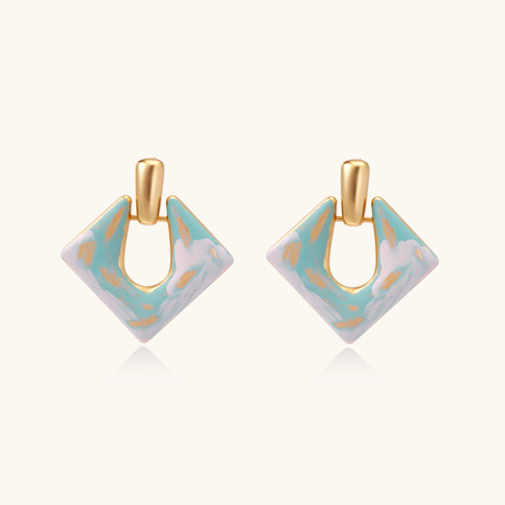 Diamond-shaped gold-plated earrings with pastel marble enamel in turquoise and lavender swirls on beige background
