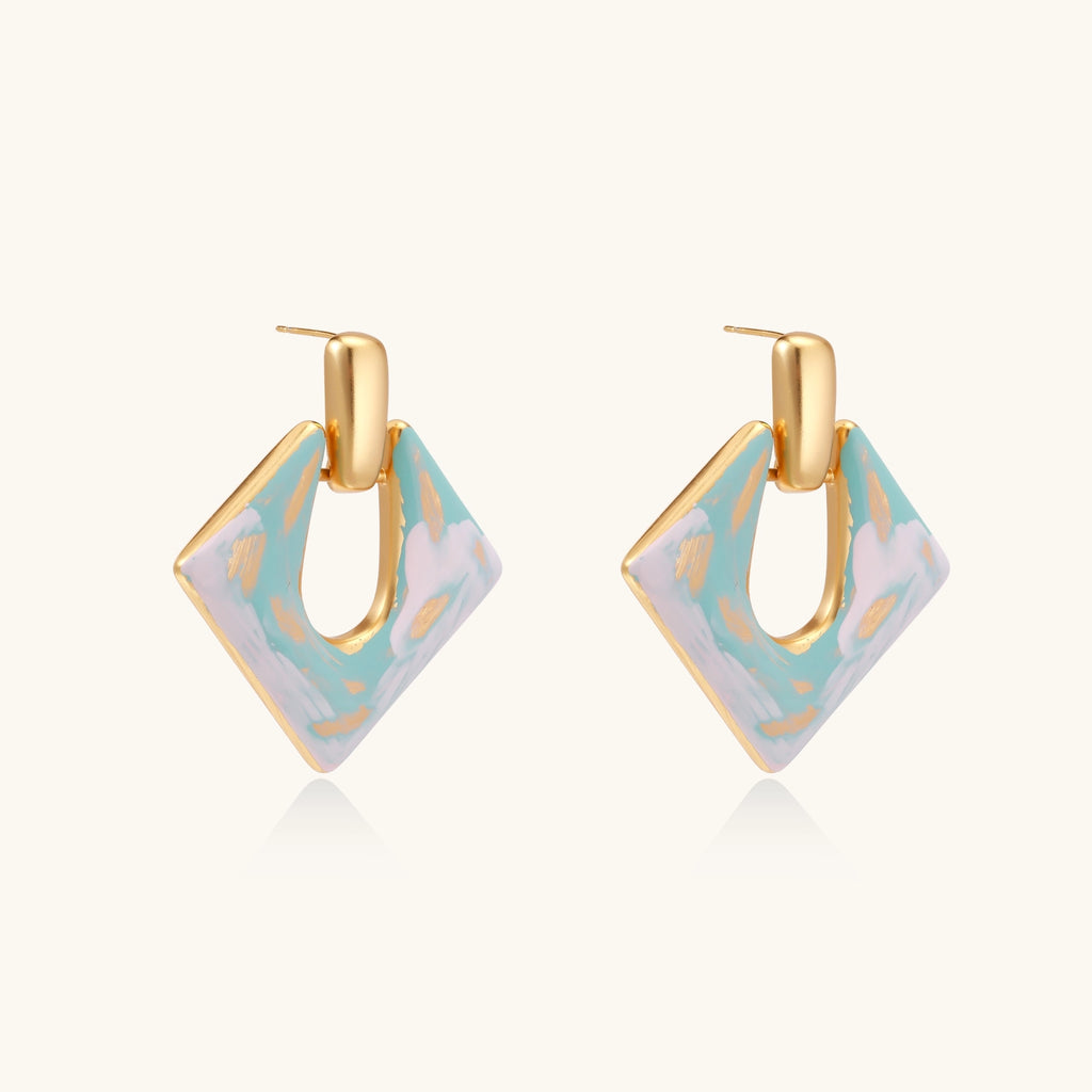Diamond-shaped gold-plated earrings with pastel marble enamel in turquoise and lavender swirls on beige background