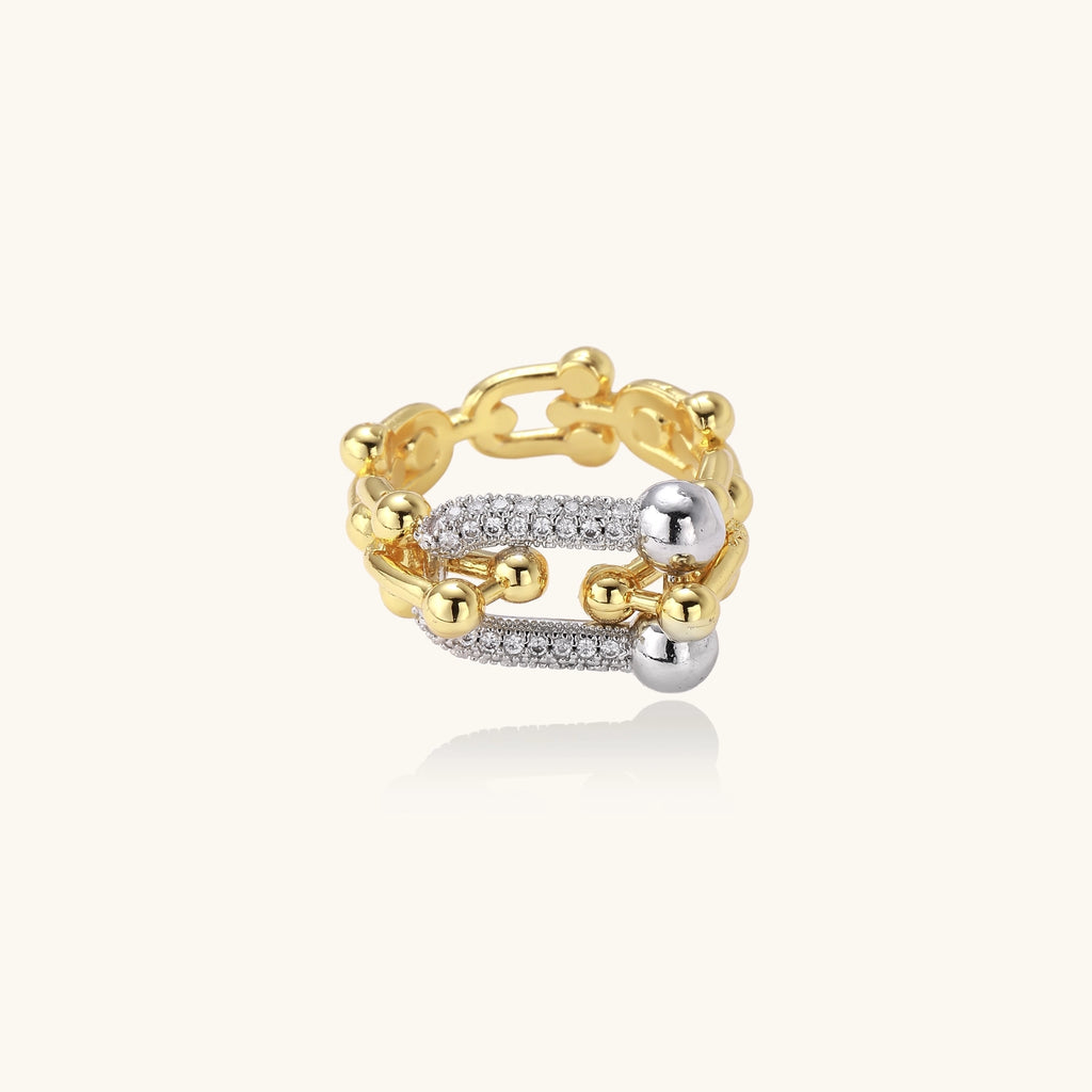 Bold gold-plated chain-link ring with cubic zirconia bars and sphere details on white background.