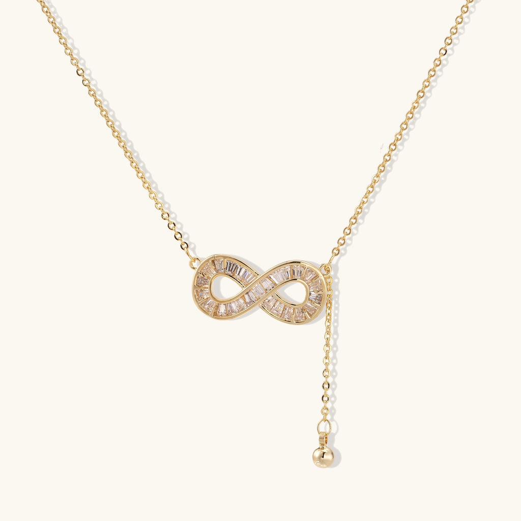 Delicate 14K gold plated infinity pendant with crystal accents on adjustable chain with small ball charm detail.