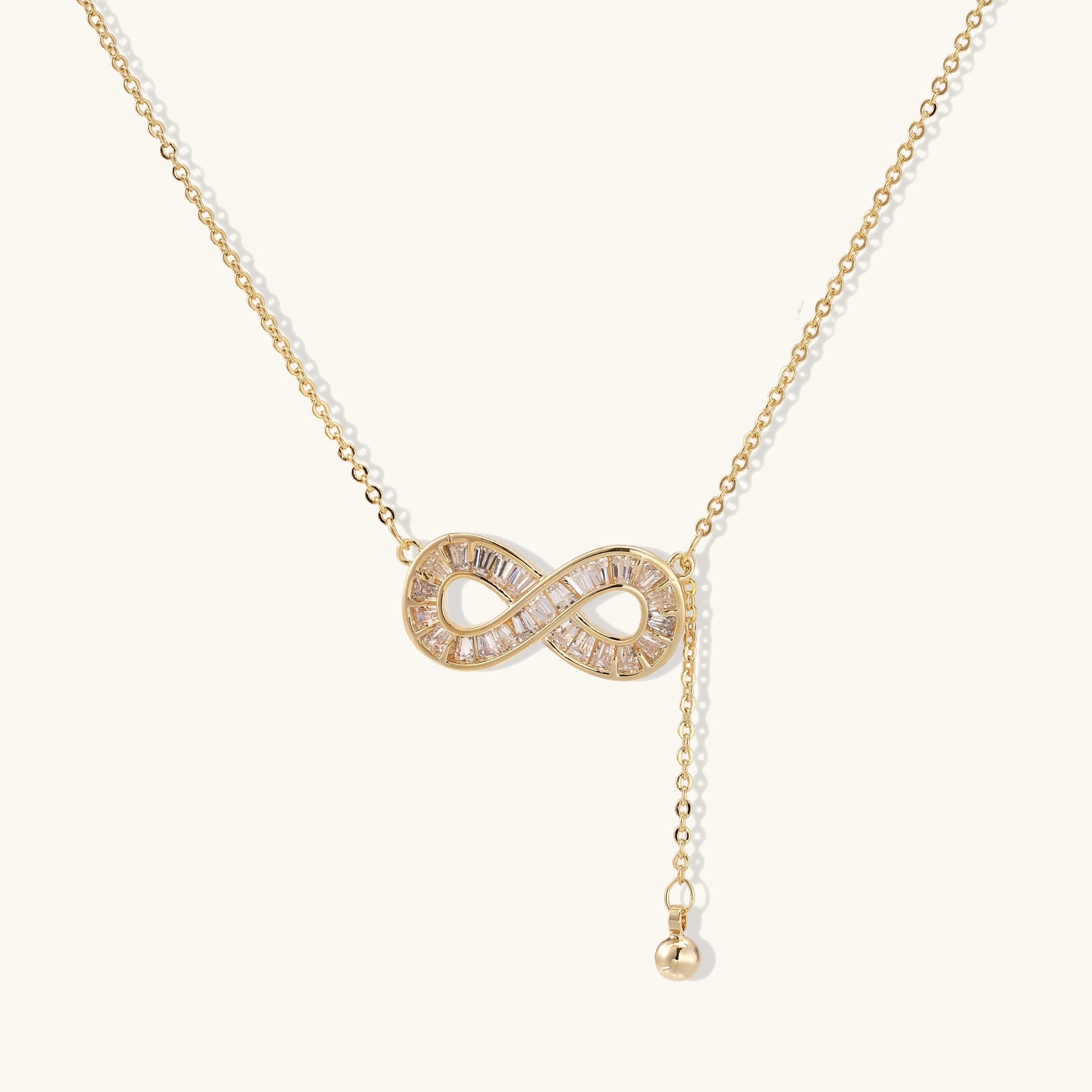 Delicate 14K gold plated infinity pendant with crystal accents on adjustable chain with small ball charm detail.