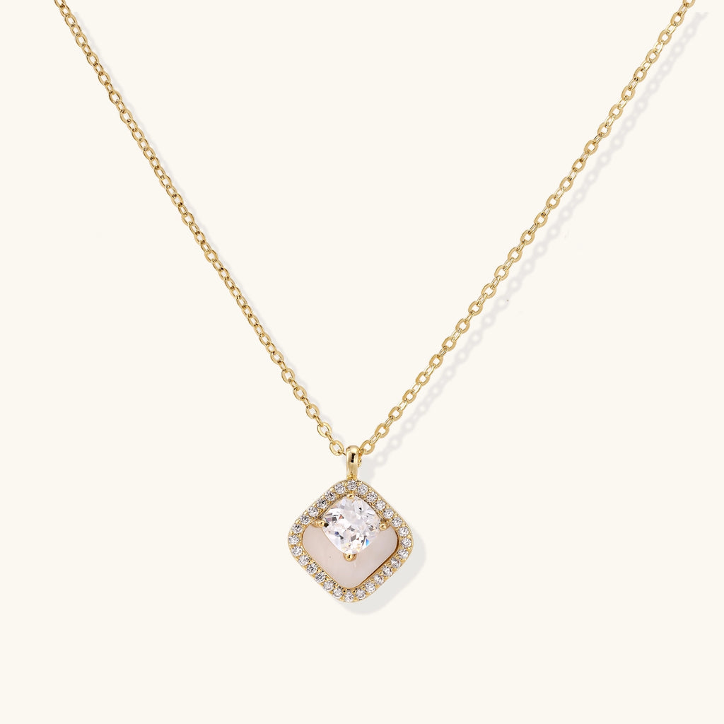 Gold-plated necklace with cushion-shaped pendant featuring a freshwater pearl surrounded by crystal halo on white background.