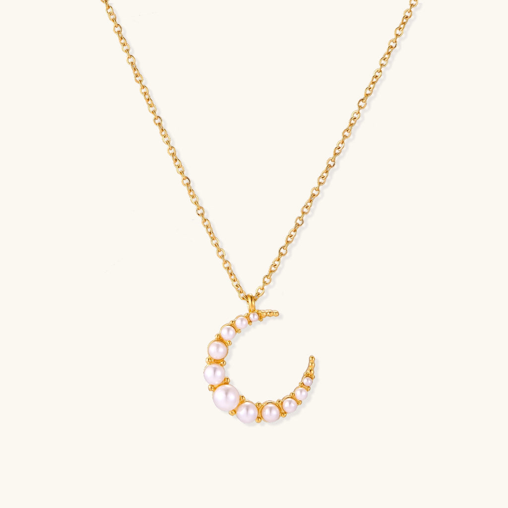 Delicate 18K gold plated necklace featuring crescent moon pendant with white shell pearl beads on neutral background.