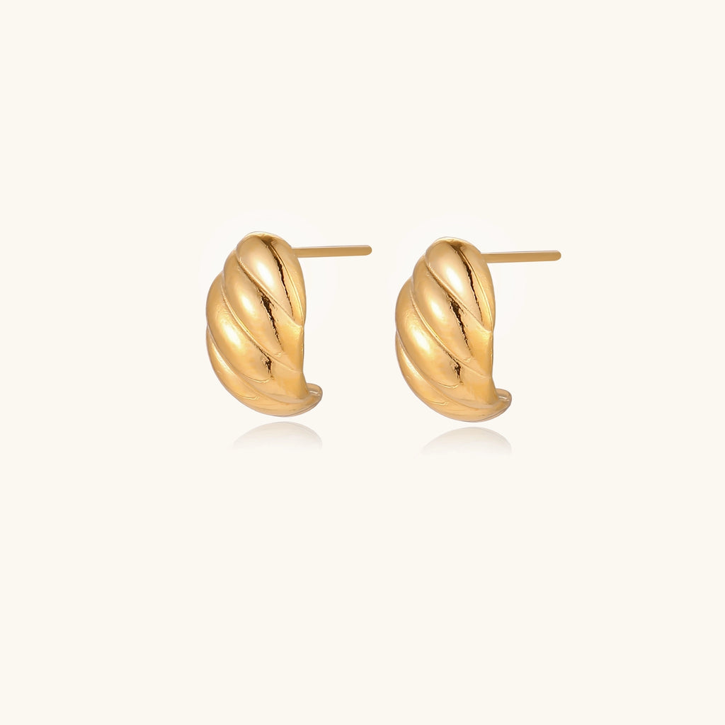 Pair of gold-plated twisted stud earrings with sculptural spiral design displaying elegant curved ridges on cream background.