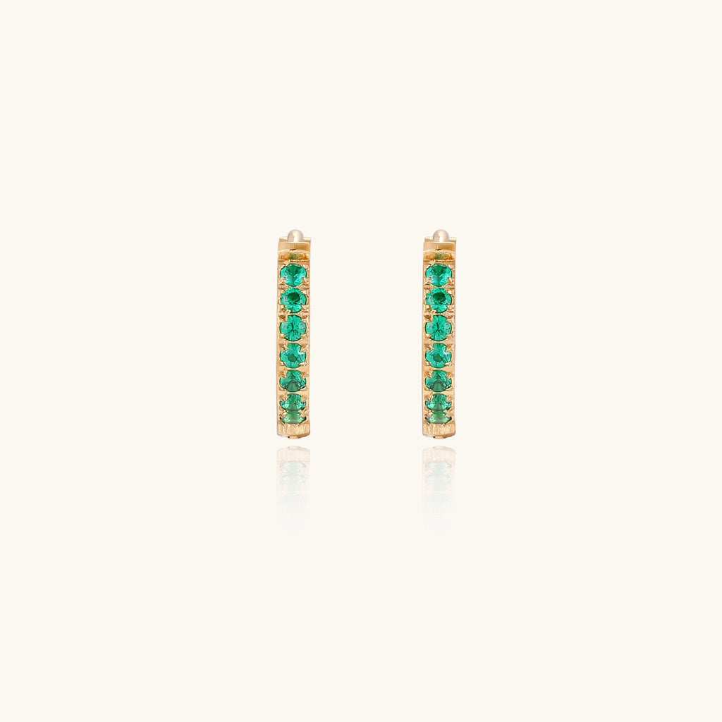 Small gold-plated huggie hoop earrings with emerald green cubic zirconia stones, one open showing hinge mechanism