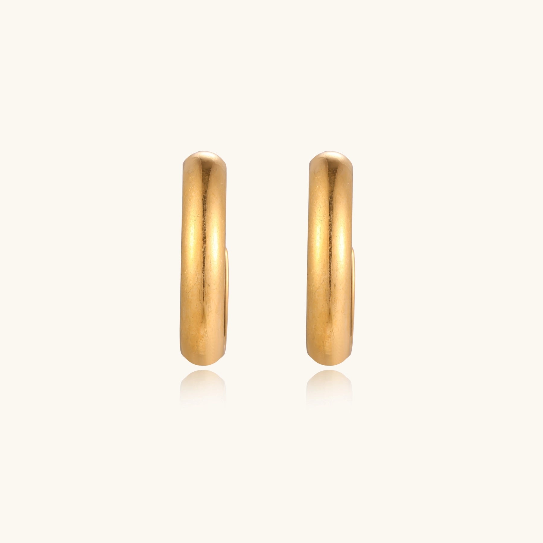 Four pairs of gold-plated stainless steel earrings including hoops and studs displayed on cream background