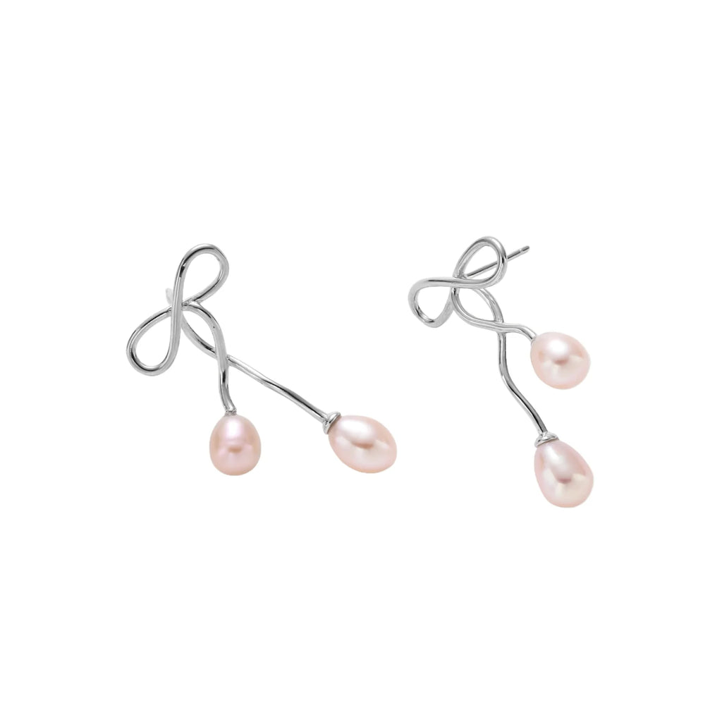 Rhodium-plated silver earrings with organic vine curves and two peachy freshwater pearls on cream background