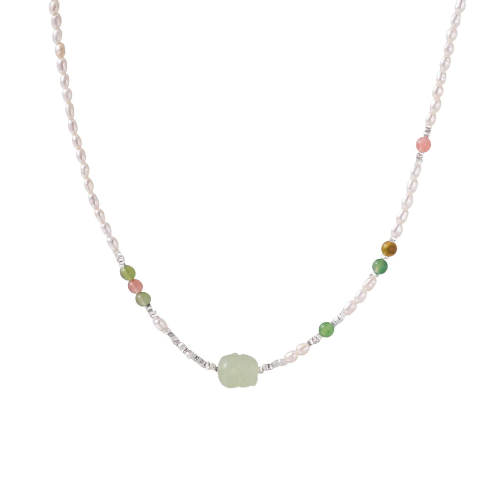 Delicate pearl necklace with pale green serpentine jade centerpiece and colorful agate beads on cream background