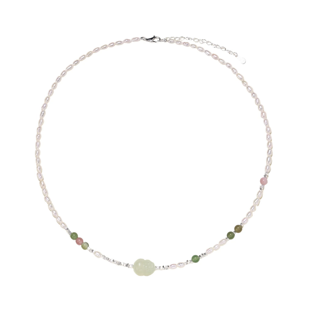Delicate pearl necklace with pale green serpentine jade centerpiece and colorful agate beads on cream background