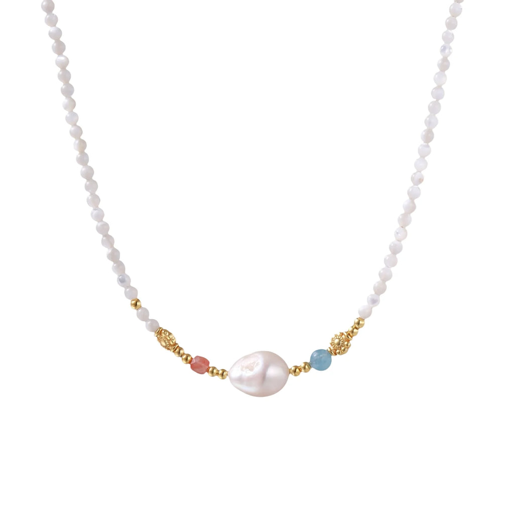 Delicate white beaded necklace with baroque pearl center, gold accents, and coral and aqua gemstones on cream background.