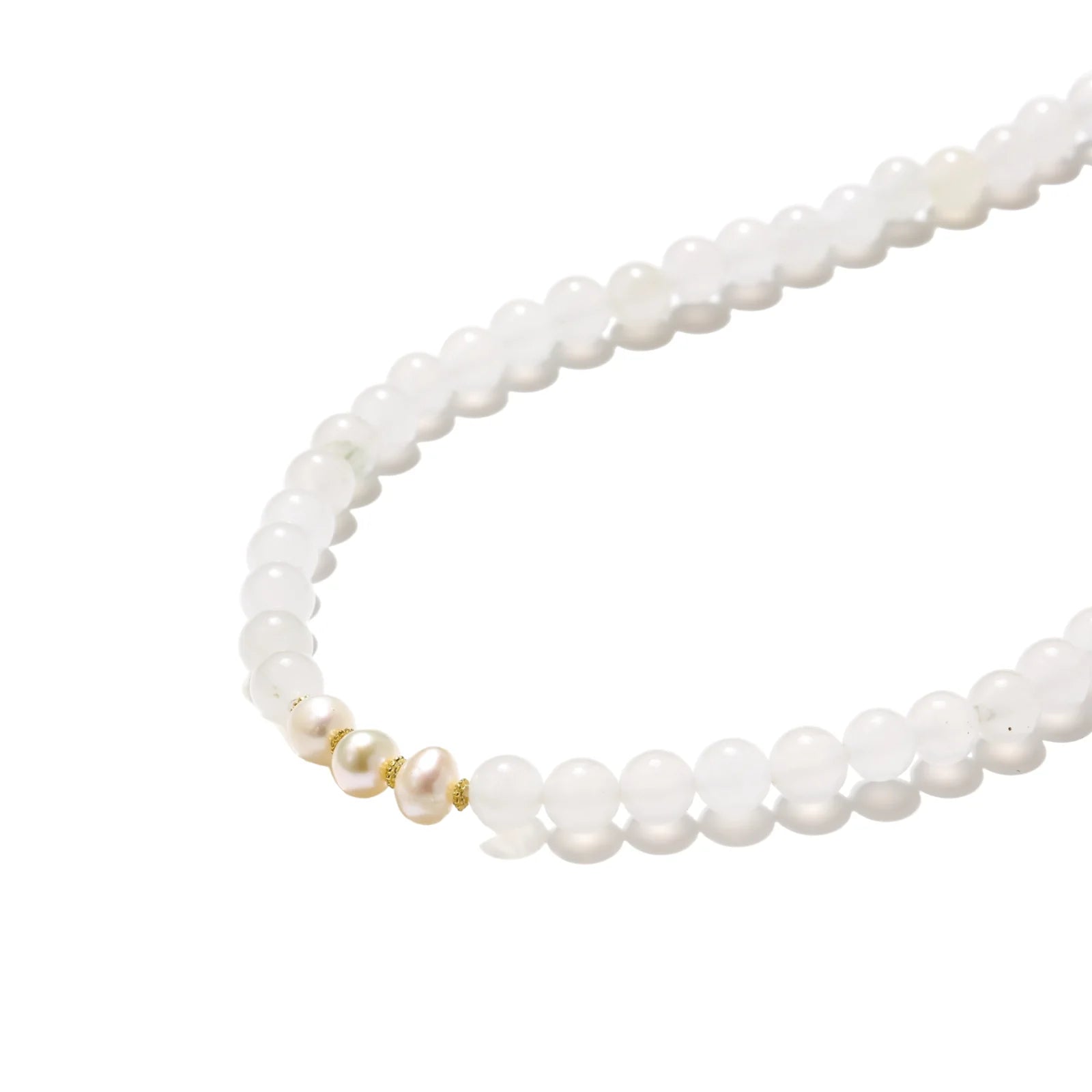 Three layered white beaded bracelets with carved orange agate lotus centerpiece and freshwater pearls on cream background.