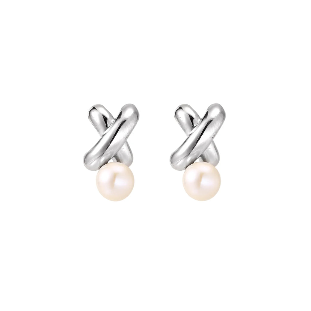 Rhodium-plated silver earrings with twisted X design and freshwater pearl drops on beige background