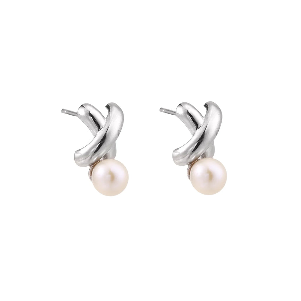 Rhodium-plated silver earrings with twisted X design and freshwater pearl drops on beige background